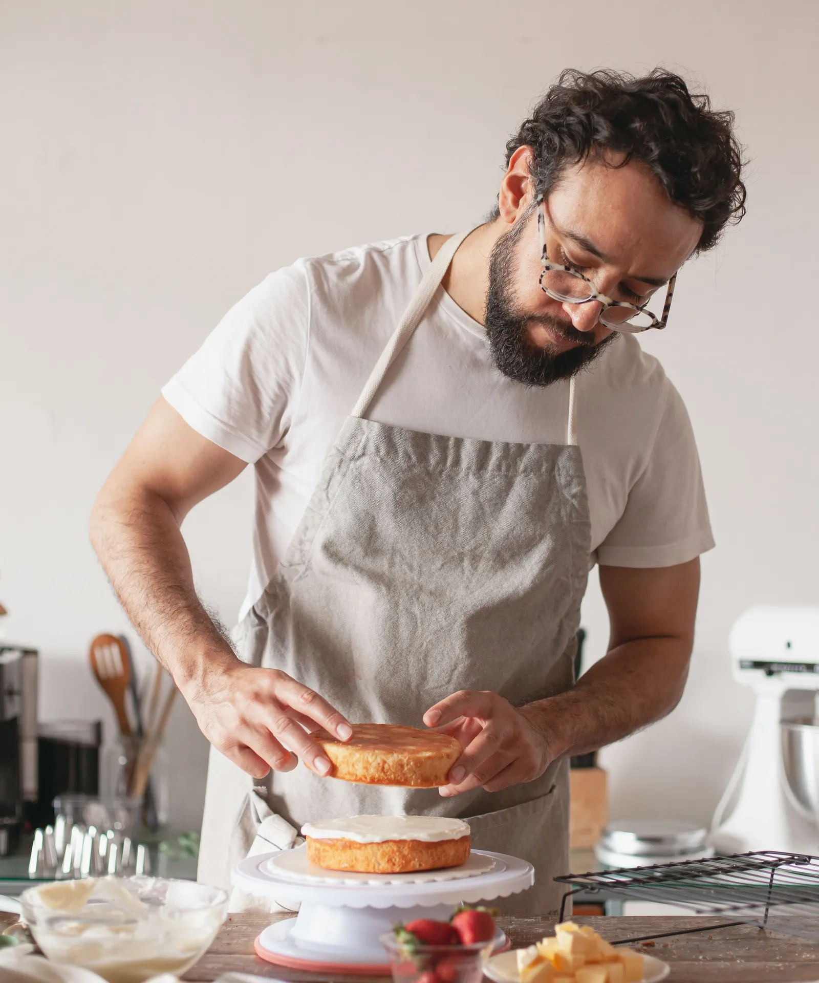 A baker piping icing onto a freshly decorated cake