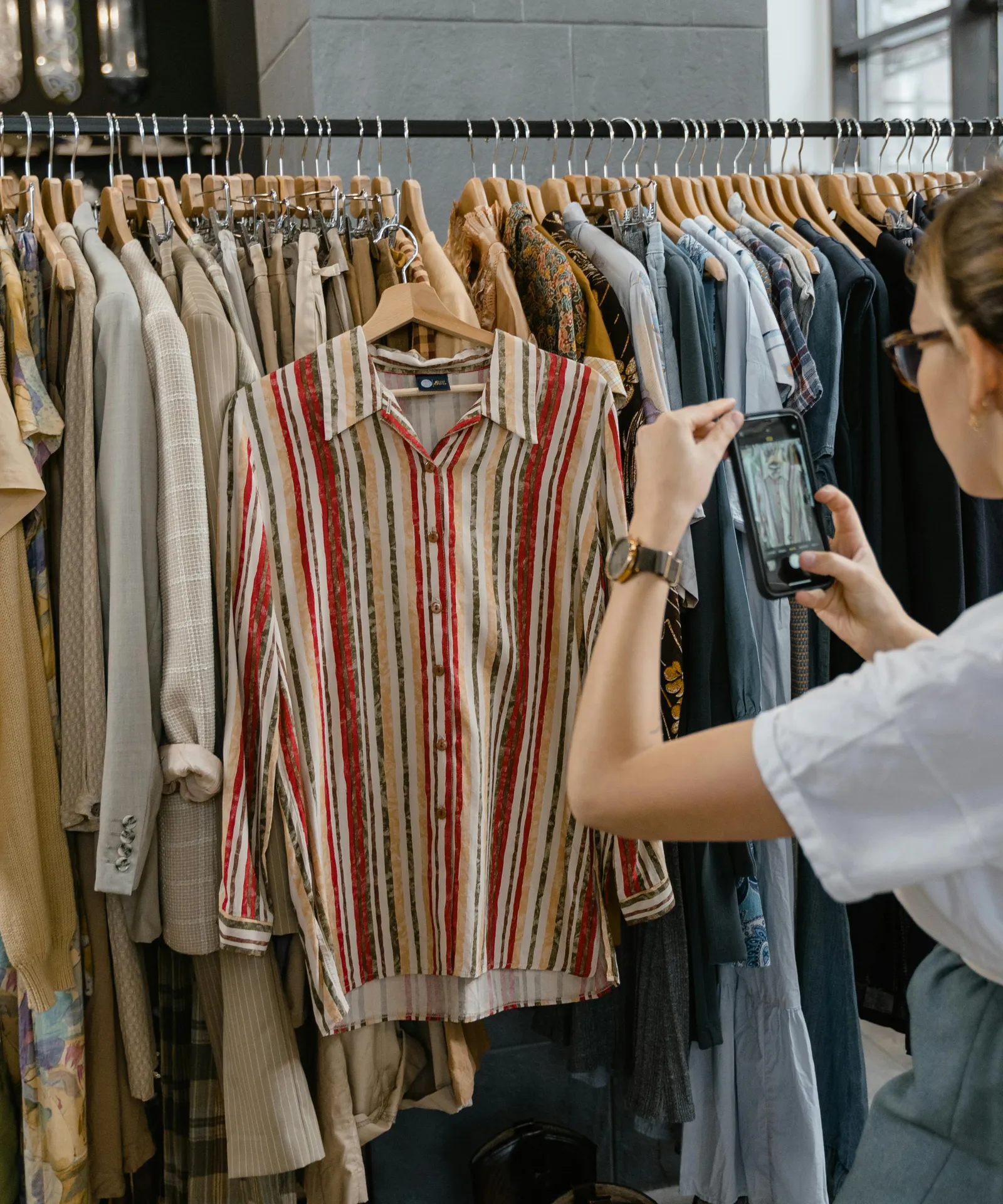A shop owner photographing clothes on a rack