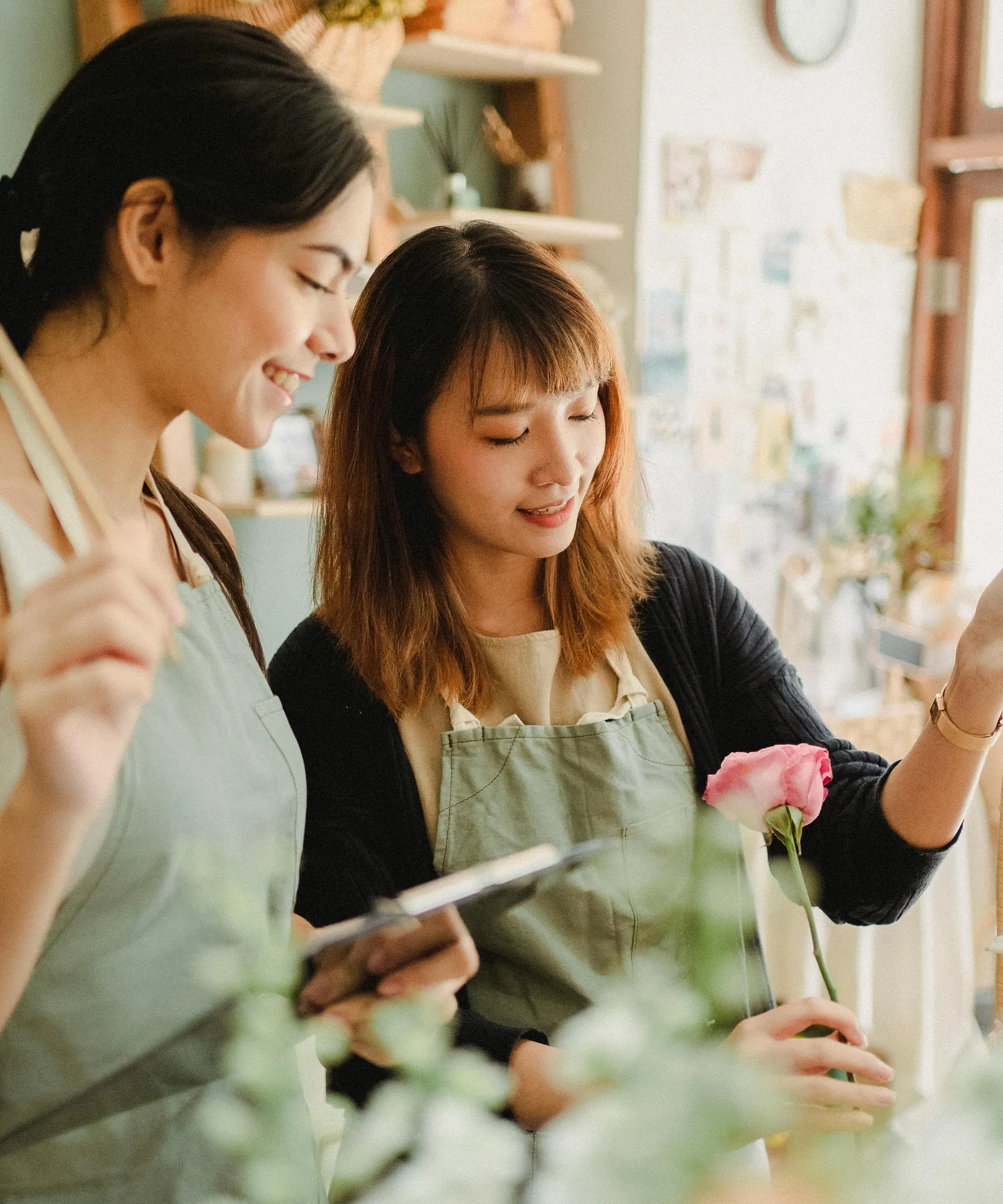 Two florists looking at a tablet among buckets of flowers
